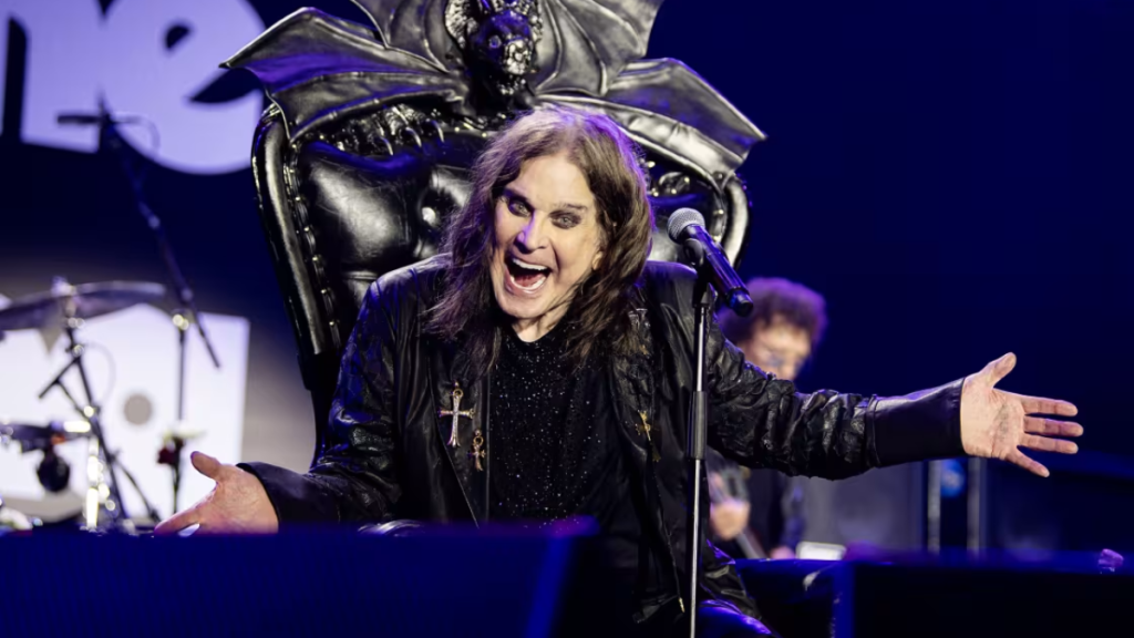 Ozzy Osbourne on stage in his recent years, wears black, with iconic round sunglasses.